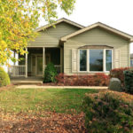 Front exterior of house with pastel green siding, large bay window, and covered front porch