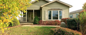 Front exterior of house with pastel green siding, large bay window, and covered front porch