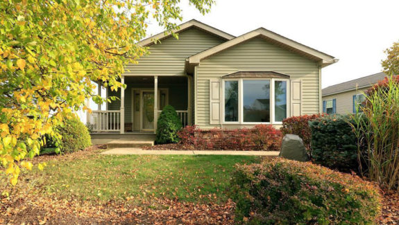 Front exterior of house with pastel green siding, large bay window, and covered front porch