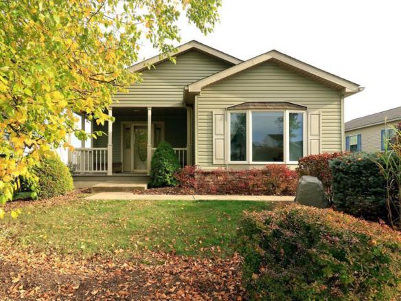 Front exterior of house with pastel green siding, large bay window, and covered front porch