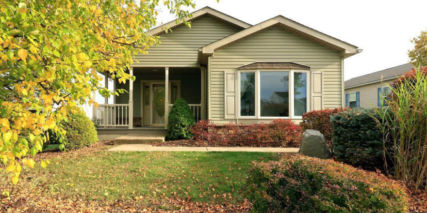 Front exterior of house with pastel green siding, large bay window, and covered front porch