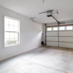 an empty garage with two windows and a door