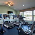 an exercise room with treadmills and television