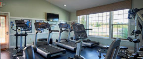 an exercise room with treadmills and television