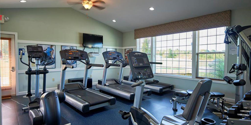 an exercise room with treadmills and television