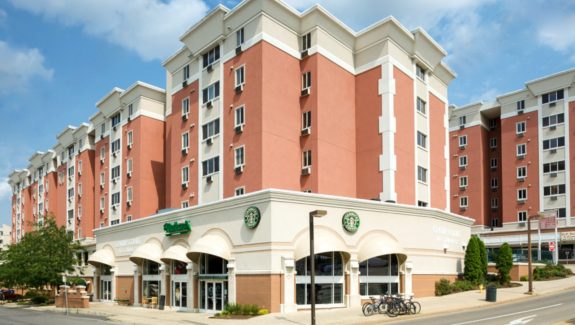 A luxury apartment building with a starbucks coffee shop on the corner