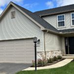 a house with tan siding, a driveway and a two-car garage