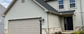 a house with tan siding, a driveway and a two-car garage