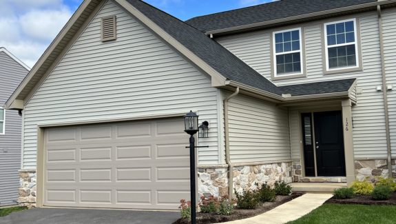 a house with tan siding, a driveway and a two-car garage