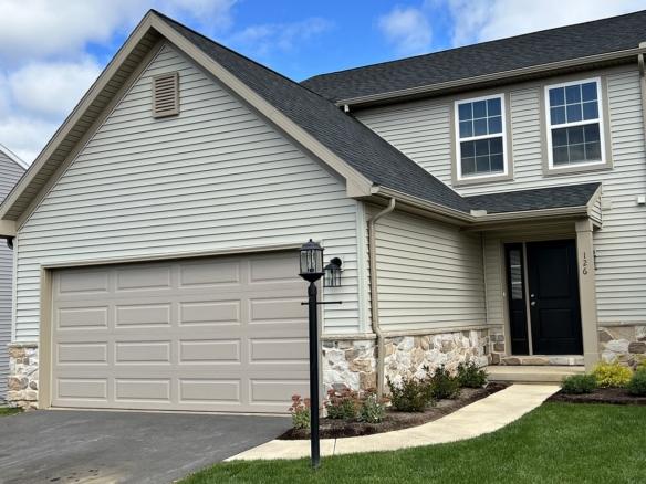 a house with tan siding, a driveway and a two-car garage