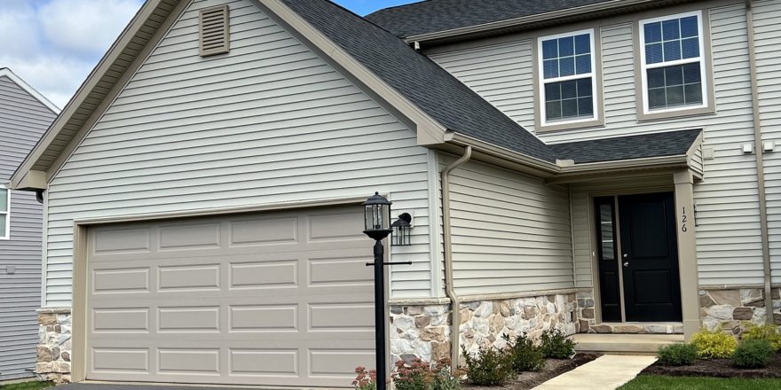 a house with tan siding, a driveway and a two-car garage