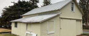 a yellow building with a metal roof and windows