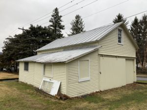 a yellow building with a metal roof and windows