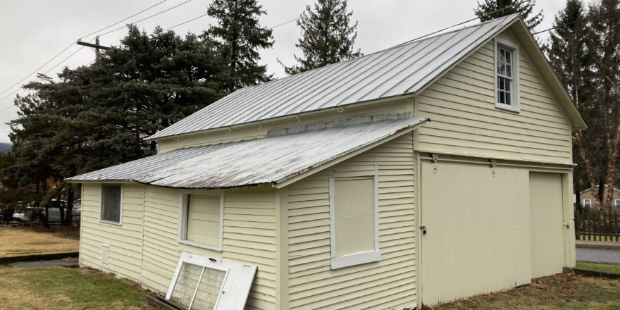 a yellow building with a metal roof and windows