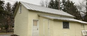 a small yellow building with a metal roof