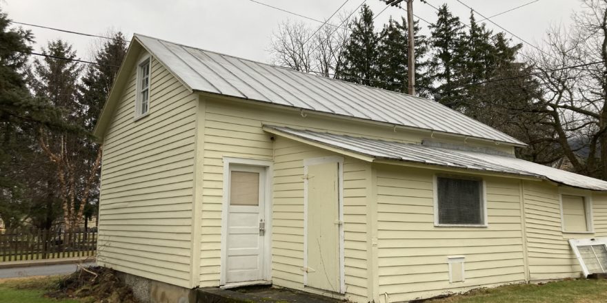 a small yellow building with a metal roof