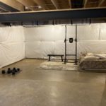 a large room with concrete floor, a bed, and some exercise gear