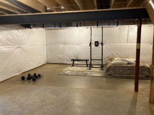 a large room with concrete floor, a bed, and some exercise gear