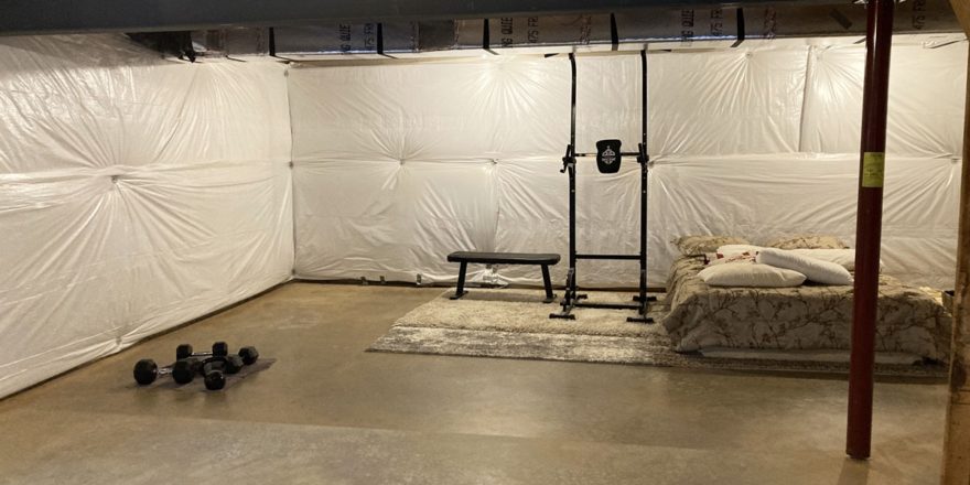 a large room with concrete floor, a bed, and some exercise gear