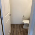 a white toilet in a bathroom on a wooden floor