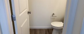 a white toilet in a bathroom on a wooden floor