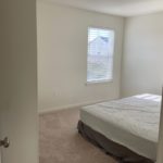an empty bedroom with a bed and window