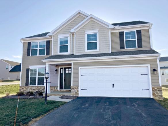 a two story house with tan siding and a two-car garage with a white bay door.