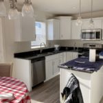 a kitchen with a small dining table, white cabinets, and stainless steel appliances