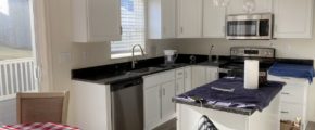 a kitchen with a small dining table, white cabinets, and stainless steel appliances