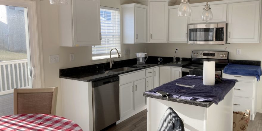 a kitchen with a small dining table, white cabinets, and stainless steel appliances