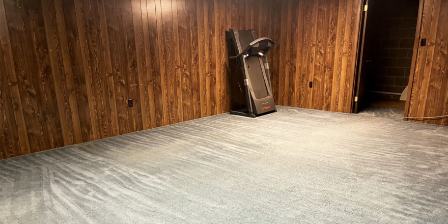 an empty room with beige carpet and wood paneling on the walls