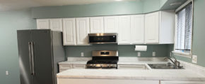 a kitchen with white cabinets, white marbled countertop, and stainless appliances