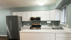 a kitchen with white cabinets, white marbled countertop, and stainless appliances