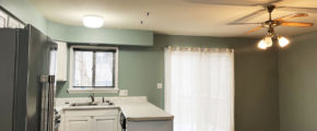 an empty kitchen with white cabinets and wood floors - stainless steel refrigerator on left and dishwasher on right