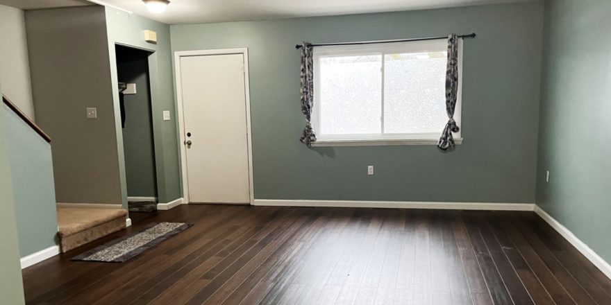 an empty living room with hard wood floors