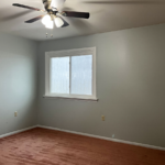 an empty room with a ceiling fan and window