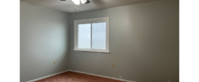 an empty room with a ceiling fan and window