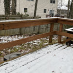 a snow covered back yard, wooden deck, and fence