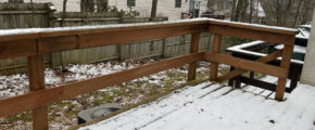 a snow covered back yard, wooden deck, and fence