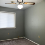 an empty room with light brown carpeting, a ceiling fan, and a window