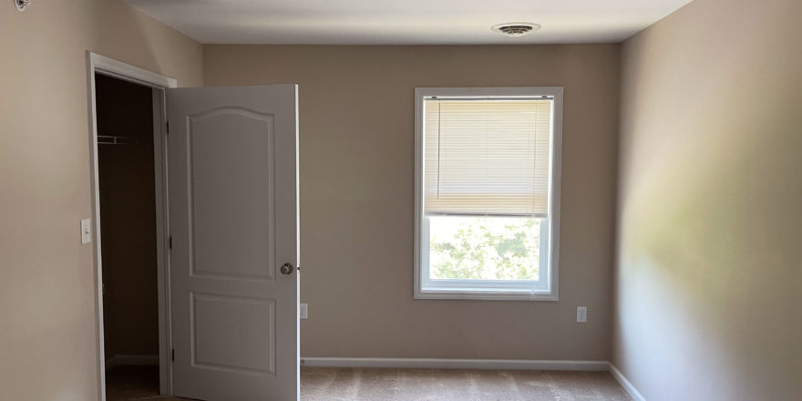 an empty room with a closet and a window