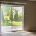 an empty living room with beige carpet and sliding glass doors