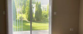 an empty living room with beige carpet and sliding glass doors