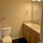 a white toilet sitting next to a double bathroom sink