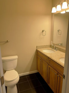 a white toilet sitting next to a double bathroom sink