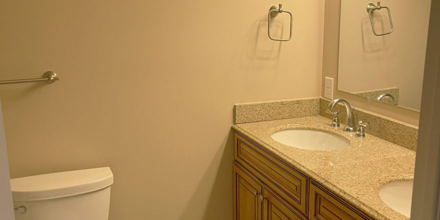 a white toilet sitting next to a double bathroom sink