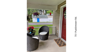 a porch with two chairs and a door