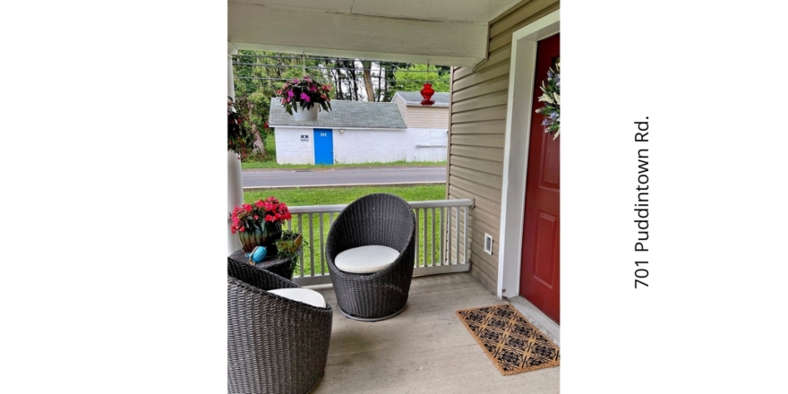 a porch with two chairs and a door