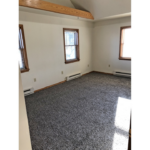 an empty room with two windows and carpet