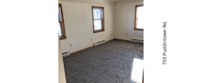 an empty room with two windows and carpet